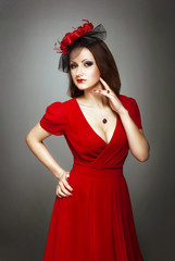 Lady in red dress and  black veil on the dark background.