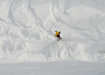 Jump of snowboarder at descent from mountain