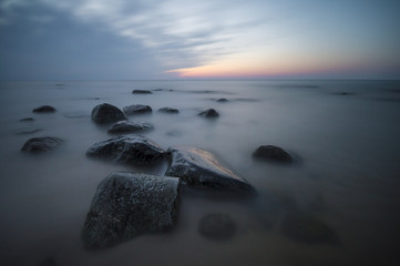Fototapety  morskie głazy na plaży po zachodzie słońca