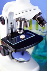 Microscope and laboratory sample, close-up on color background