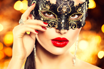 Sexy woman wearing carnival mask over holiday glowing background
