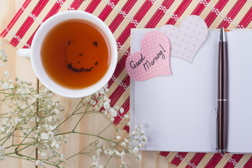 open notebook with a cup of tea on striped napkin