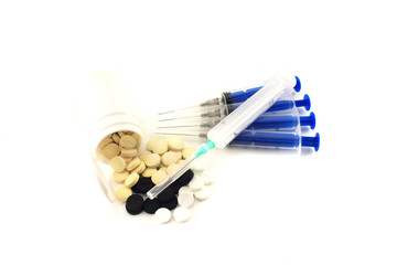 A handful of scattered tablets surrounded by syringes. Isolated