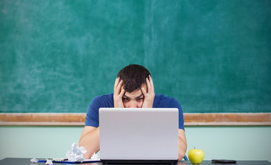 Stressed overworked man studying in front of notebook.