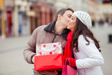Young man kissing his girlfriend and giving her presents