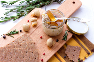 Chicken pate in jar and crispbread on wood cutting board