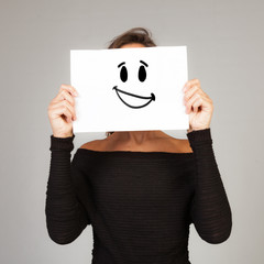 woman hiding behind a sheet of paper