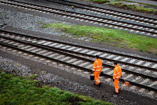 Two workers walking along railroad tracks