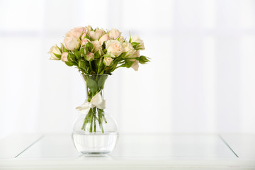 Beautiful bouquet of flowers in vase on window background
