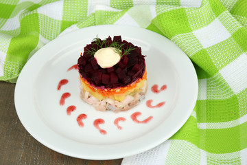 Russian herring salad on plate on wooden table background