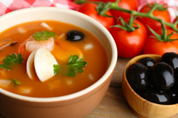 Tasty soup with shrimps, mussels, tomatoes and black olives in