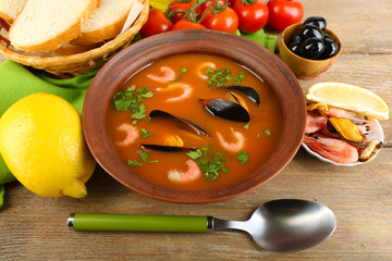 Tasty soup with shrimps, mussels, tomatoes and black olives in