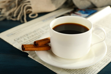 Cup of coffee with newspaper, plaid and cinnamon