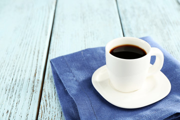 Cup of coffee on blue napkin on color wooden background