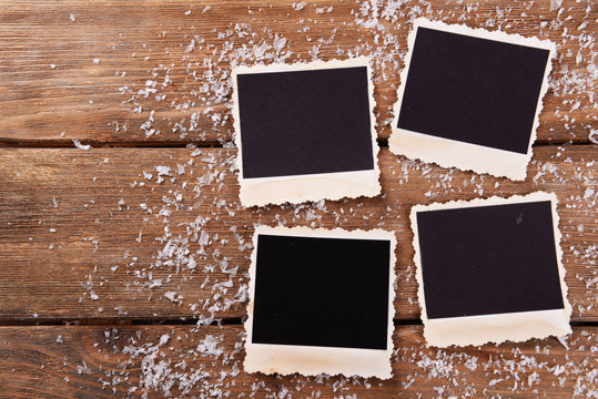 Blank photo frames and snowflakes on wooden table background