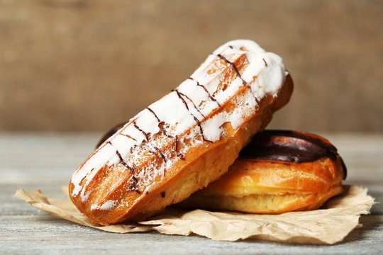 Tasty eclairs on wooden table, close up