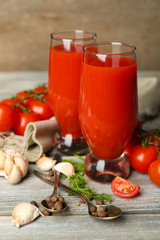Obraz na płótnie Canvas Glasses of tasty tomato juice and fresh tomatoes on wooden