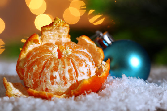 Fresh ripe mandarin on snow, on lights background