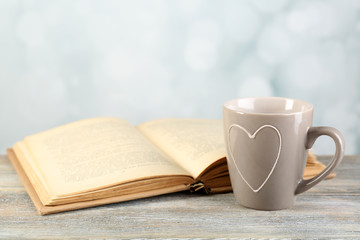 Cup of tea and book on table, on light background