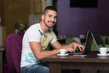 Smiling Young Student In Cafe Using Laptop