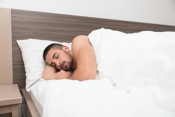 Fototapeta na wymiar Young Man Sleeping Peacefully In His Own Bed