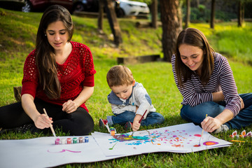 Happy Mother aunt sister and son child painting in the park