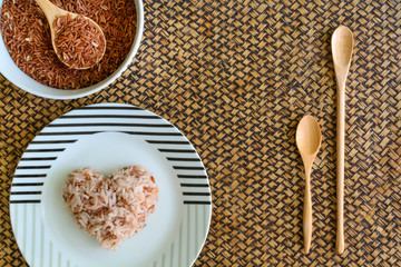 Heart shape brown rice with wooden spoon