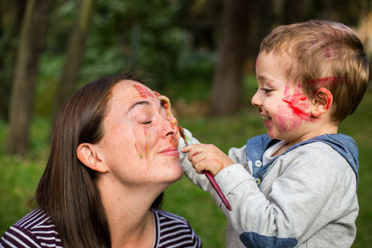 Happy child painting his mother´s face in the park