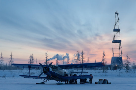 Biplane next to oil derrick on winter sunrise background