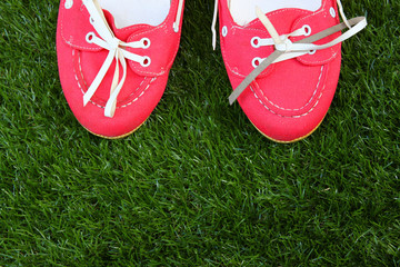 top view of red worn girl shoes over grass textured background