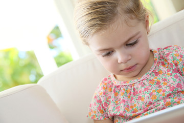 Little girl in sofa connected with digital tablet