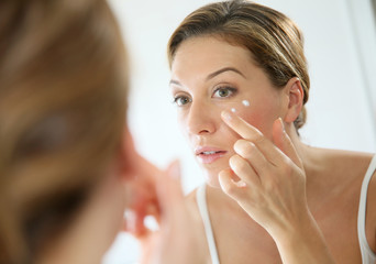 Middle-aged woman applying anti-aging cream