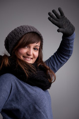 girl waving at camera with warm hat scarf and gloves