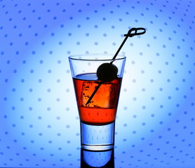 Short drink glass with red liquid and ice cubes