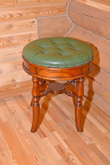 The stool with a leather upholstery stands near a timbered wall
