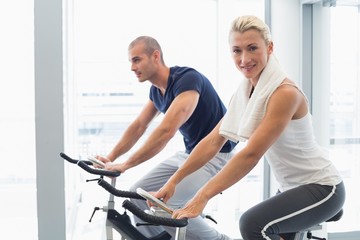Fototapeta na wymiar Fit couple working on exercise bikes at gym