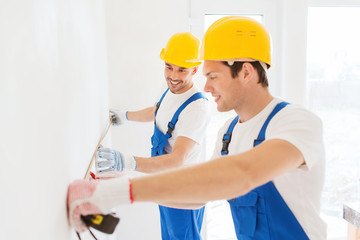 smiling builders with measuring tape indoors