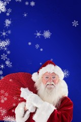 Composite image of jolly santa carries his sack