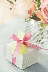 Gift box decorated with bow and roses in vase
