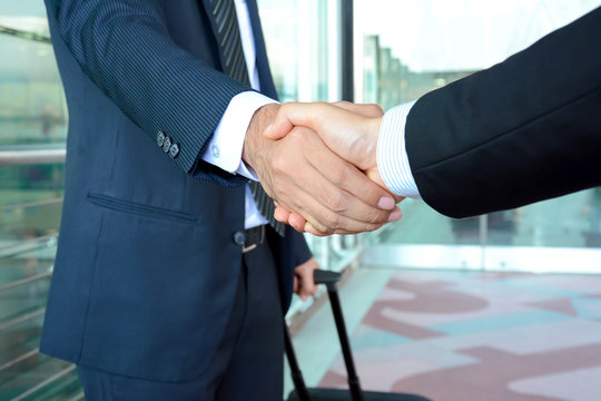 Handshake of businessmen at the airport - business trip concept