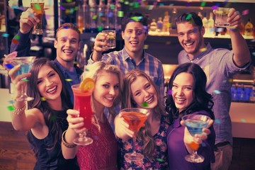 Composite image of happy friends drinking cocktails together