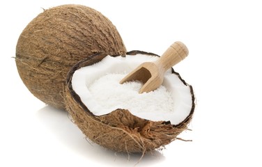 A coconut with desiccated coconut and scoop on white background