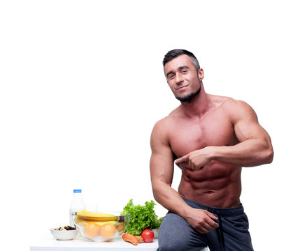 Happy muscular man pointing at healthy food