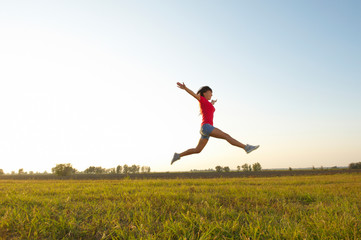 Young woman with raised arms outdoor jumping