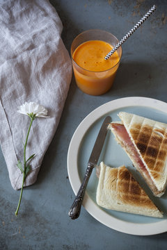 toasted sandwich with orange carrot smoothie on table