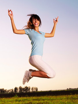 Young woman with raised arms outdoor jumping