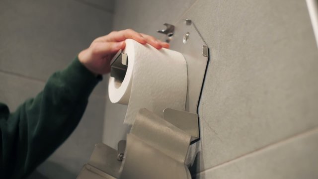Putting a toilet paper roll into container.