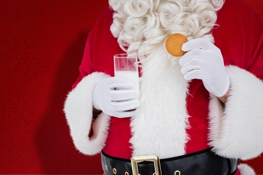 Composite image of santa holding glass of milk and cookie