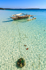 Traditional fisherman boat lying near the beach in clear water