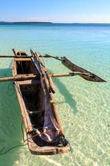 Traditional fisherman boat lying near the beach in clear water